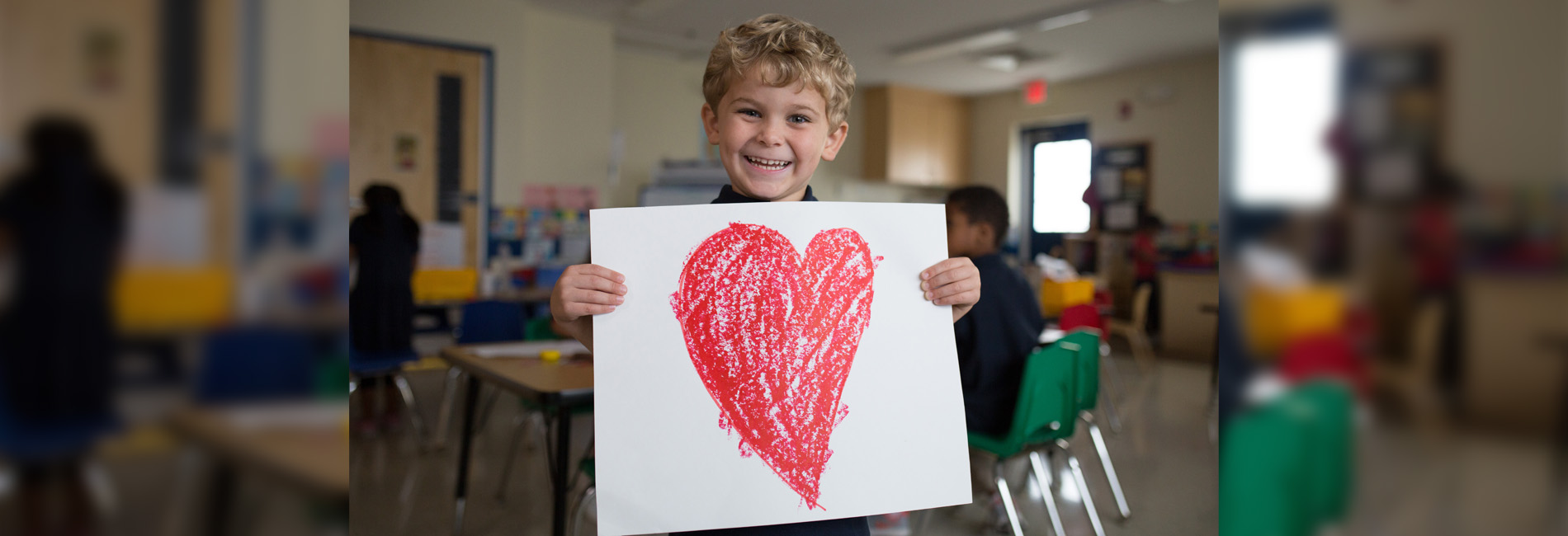 Boy holding up a drawing of a heart