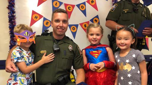 Deputy poses with three children in costumes.