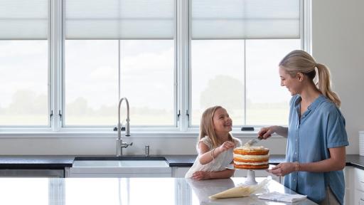 Mother and daughter icing a cake in a kitchen with Pella windows