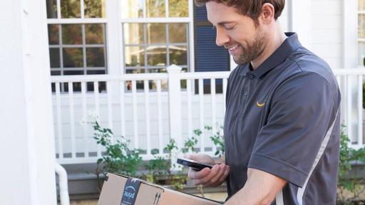 Man with an Amazon package looking at his cell phone.