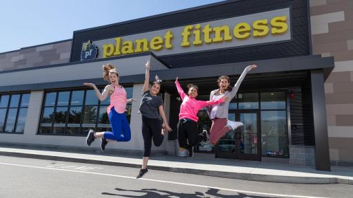 Group of females jumping in front of a Planet Fitness