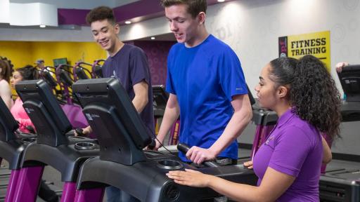 Planet Fitness worker talking with a teen using a cardio machine