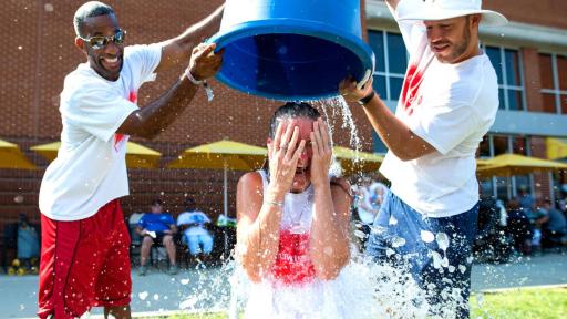 Two men pouring a bucket of ice water over a women for the ice bucket challenge