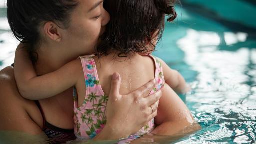 Woman holding her daughter while swimming