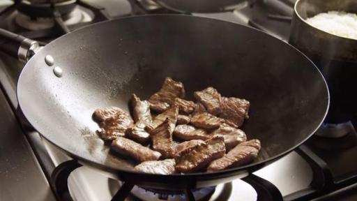 Frying pan filled with slices of beef.