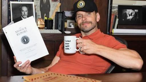 Joel McHale holding a mug and the Mooer Report