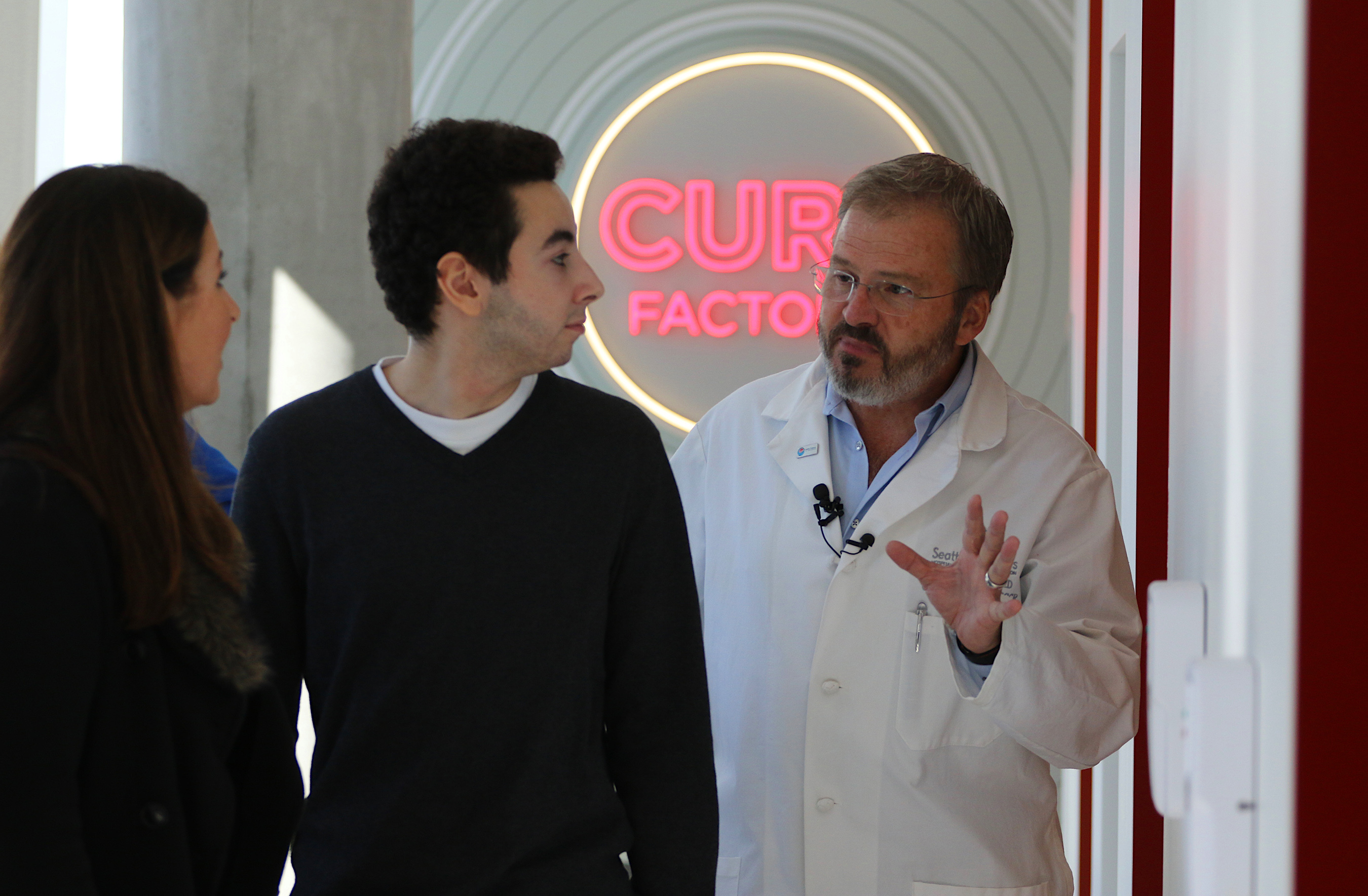 Jedd Feliciano (center), 16, a childhood leukemia survivor who received an experimental T-cell immunotherapy through a Seattle Children's clinical trial, tours the Cure Factory facility in Building Cure with his mom, Maryn Sage (left), and Dr. Michael Jensen (right), the director of the Ben Towne Center for Childhood Cancer Research at Seattle Children's Research Institute.