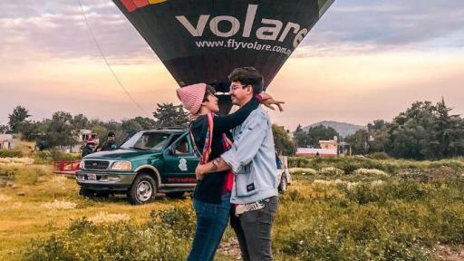 Couple hugging in front of a hot air balloon