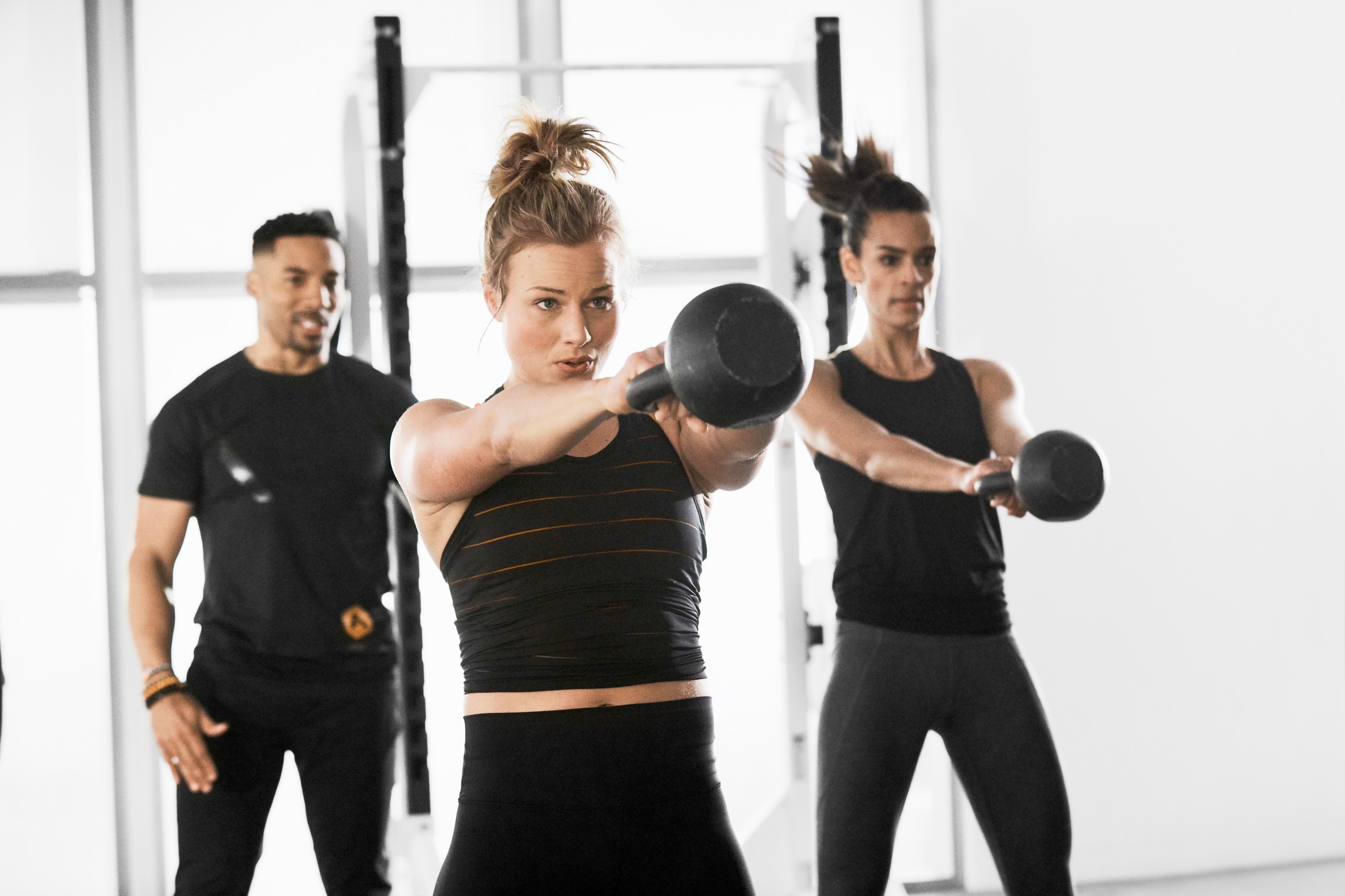 A picture of a personal trainer guiding two people in a group fitness class