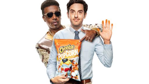 MC Hammer standing with a man in a suit who is holding a bag of Cheetos