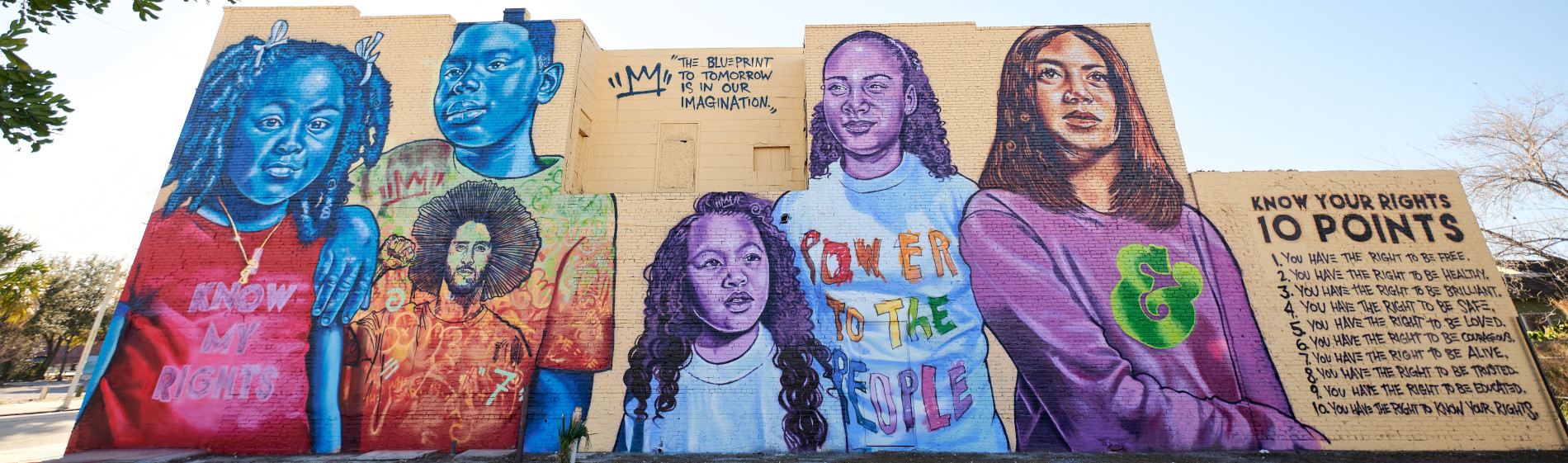 Mural on Moses White Blvd. featuring portraits of Tampa youth alongside Know Your Rights Camp volunteers