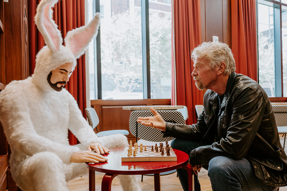 Richard Branson sitting at a table with a man in a bunnysuit.