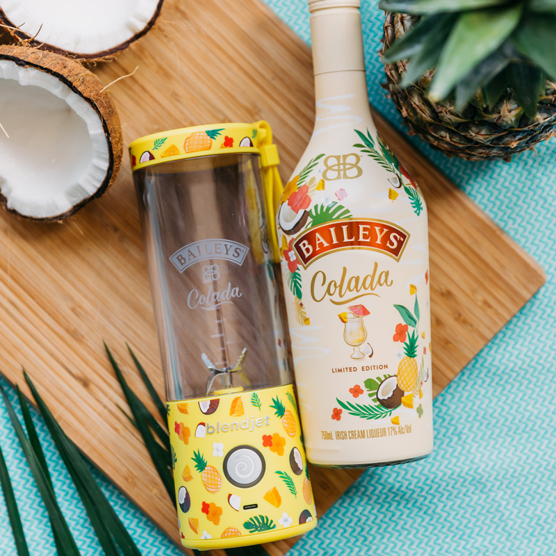 BlendJet and Bailey's Pina Colada laying on a cutting board.
