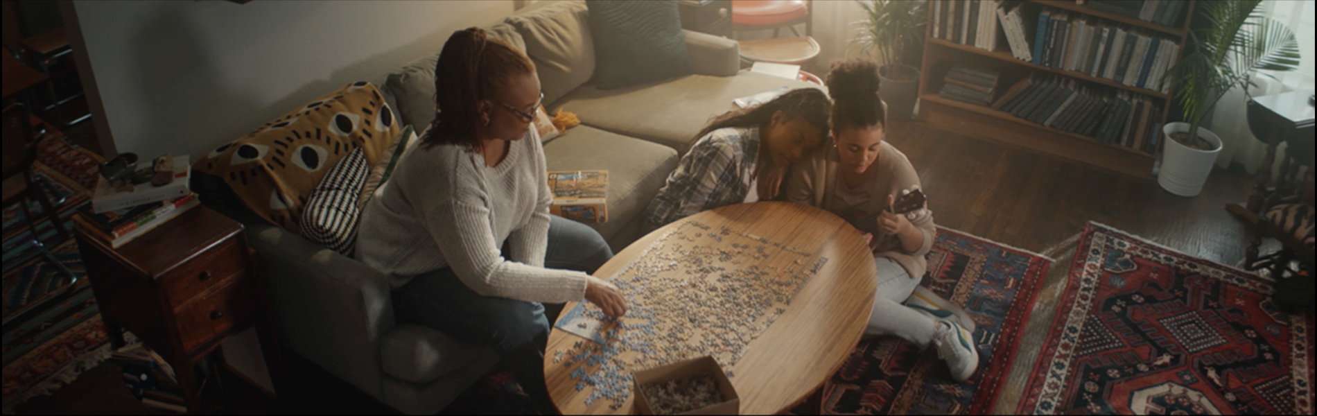 People around a living room table, putting together a puzzle