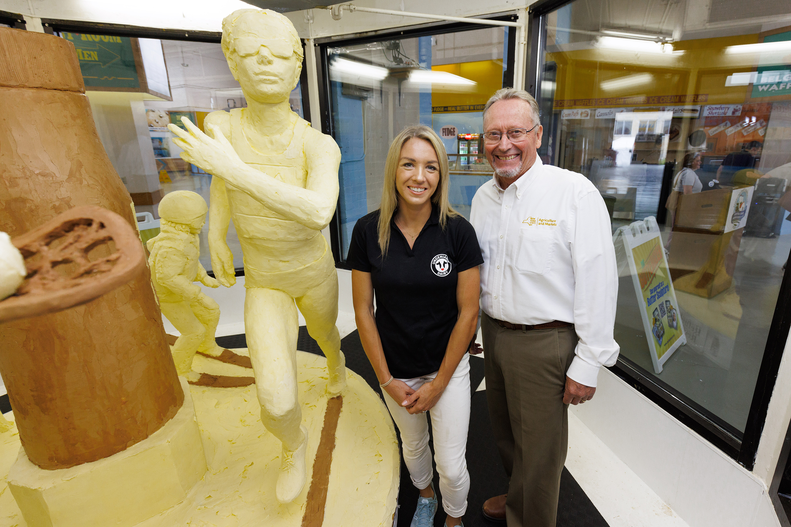 American Dairy Association North East unveiled the 54th Annual Butter Sculpture at the New York State Fair on August 23, 2022, titled Refuel Her Greatness – Celebrating the 50th Anniversary of Title IX. Participating in the unveiling were U.S. Olympian, professional runner, and dairy farmer Elle St. Pierre (left) and New York State Department of Agriculture and Markets Commissioner Richard A. Ball.