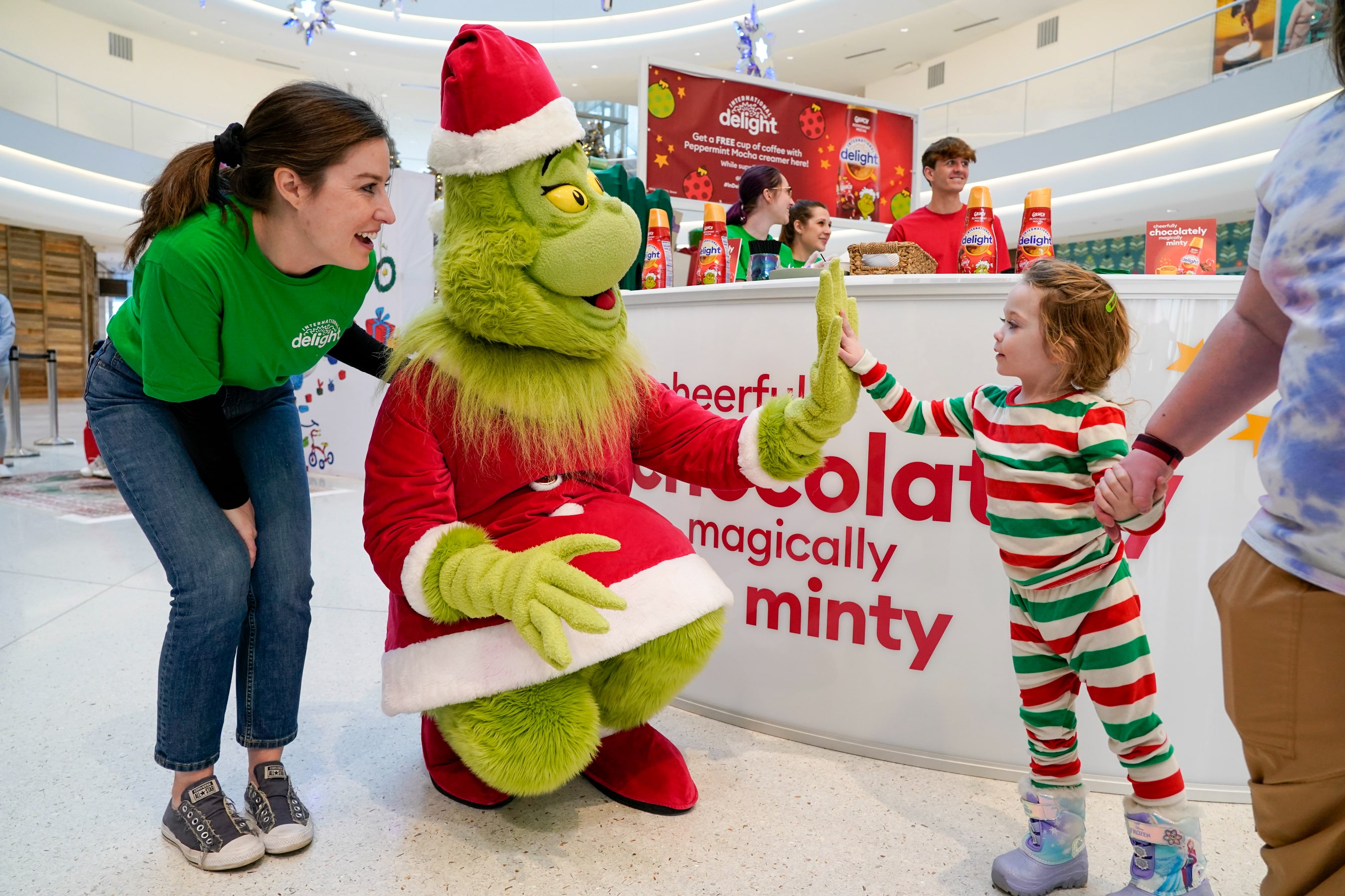 Evelynn Taylor, 4, high fives the Grinch, who was at Mall of America on Thursday, Dec. 8, 2022, serving up free coffee with International Delight Grinch Peppermint Mocha creamer.