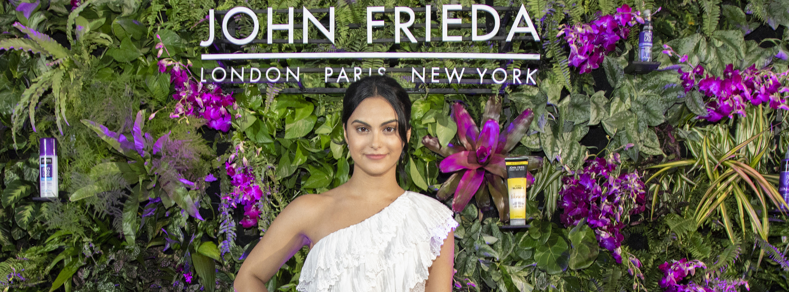 Banner image of Camila Mendes standing in front of a hedge wall