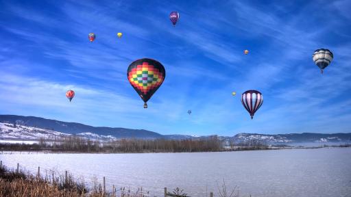 10 montgolfières volant dans un ciel d'hiver bleu brillant.