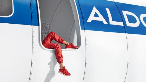 Legs of someone lying down dangling from an airplane door, highlighting orange shoes.