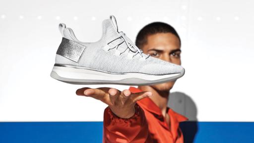 Man presenting a white shoe that hovers just above his hand.