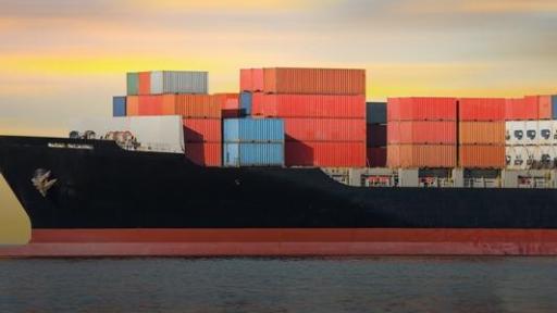 Image of cargo container ship at sea at sunset