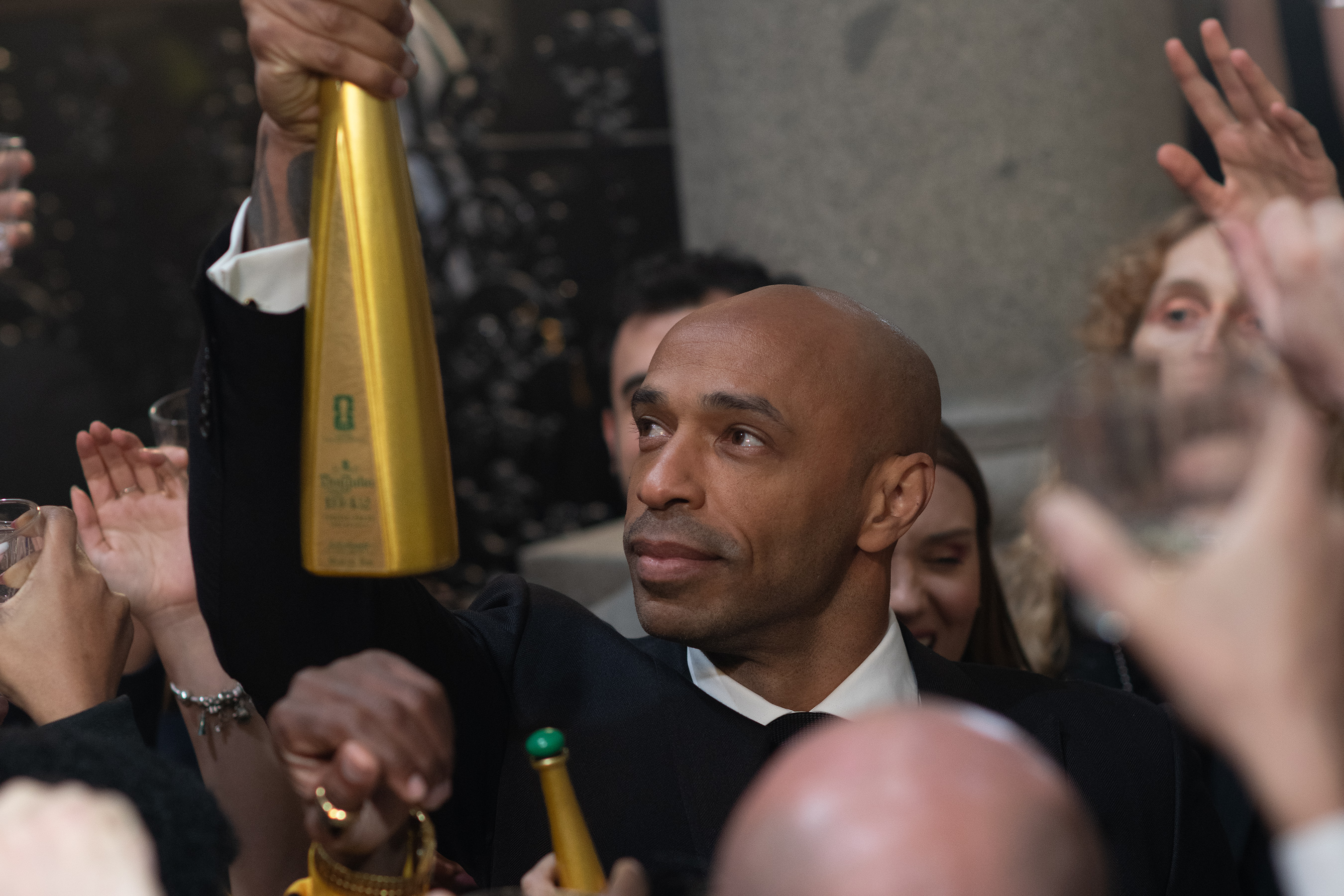 Bottle in hand, he moves through the crowd, pauses to kiss it in homage to his iconic 1998 FIFA World Cup<sup>&trade;</sup> victory with France, and then raises it triumphantly, a moment that sends the celebration soaring.