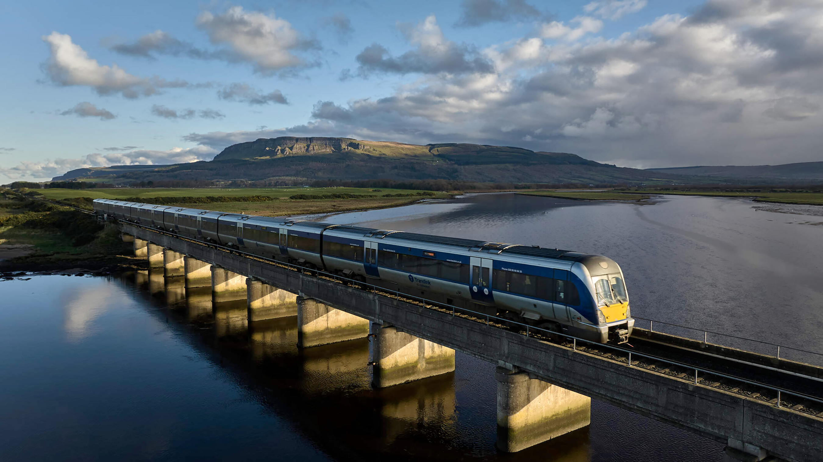 Train on railway crossing over River Roe near Binevenagh Mountain Co Londonderry